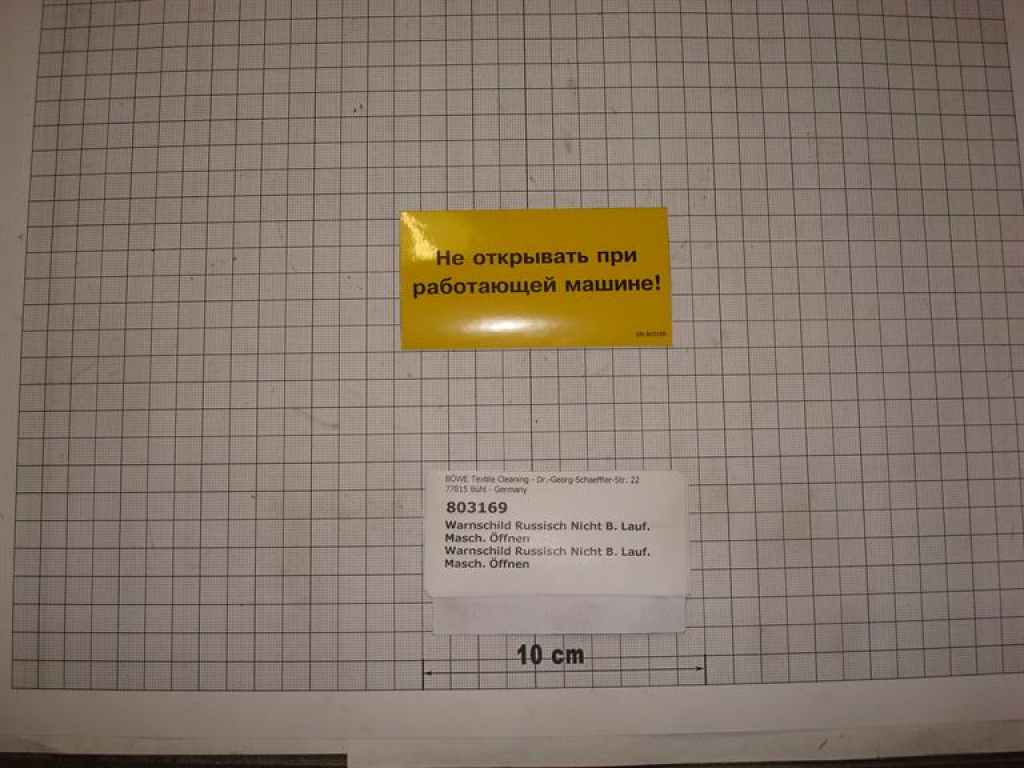 Warnschild Russisch: "Nicht bei laufender Maschine öffnen"